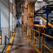 Interior amplo de uma fábrica moderna, com máquinas industriais e sistemas de esteiras transportadoras