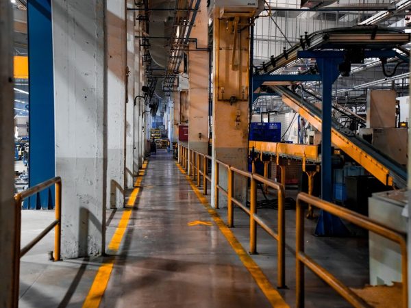 Interior amplo de uma fábrica moderna, com máquinas industriais e sistemas de esteiras transportadoras