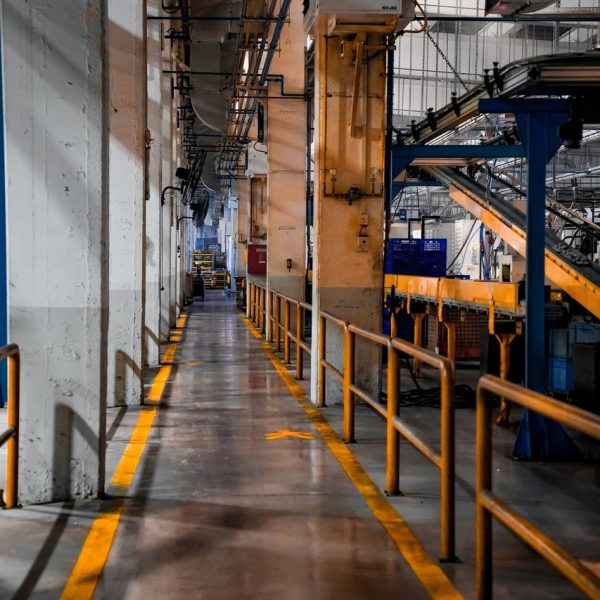 Interior amplo de uma fábrica moderna, com máquinas industriais e sistemas de esteiras transportadoras