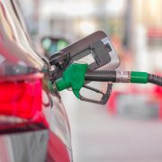 Bico de abastecimento inserido no tanque de um carro em um posto de combustíveis.