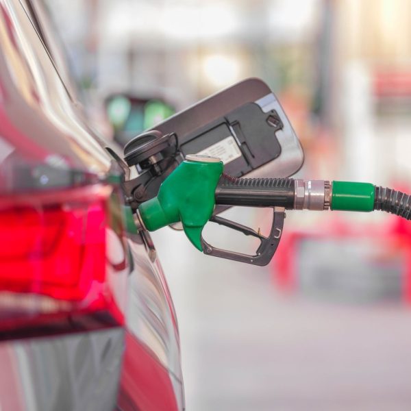 Bico de abastecimento inserido no tanque de um carro em um posto de combustíveis.