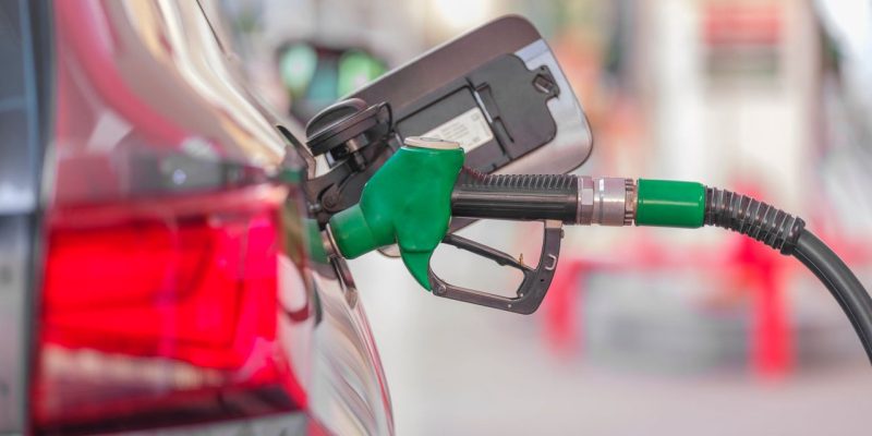 Bico de abastecimento inserido no tanque de um carro em um posto de combustíveis.