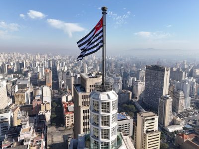 Vista aérea do horizonte de São Paulo com a bandeira do estado em destaque.