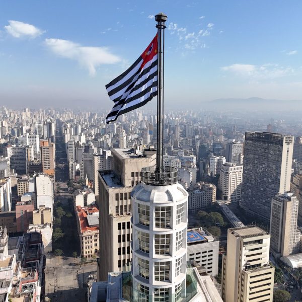 Vista aérea do horizonte de São Paulo com a bandeira do estado em destaque.