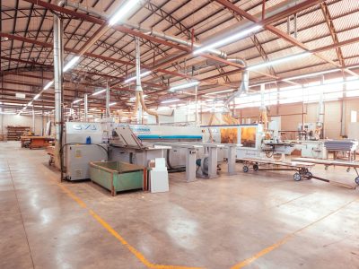 Vista ampla de uma fábrica organizada, com máquinas industriais e áreas de produção.