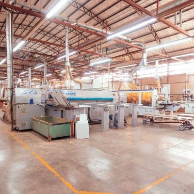 Vista ampla de uma fábrica organizada, com máquinas industriais e áreas de produção.