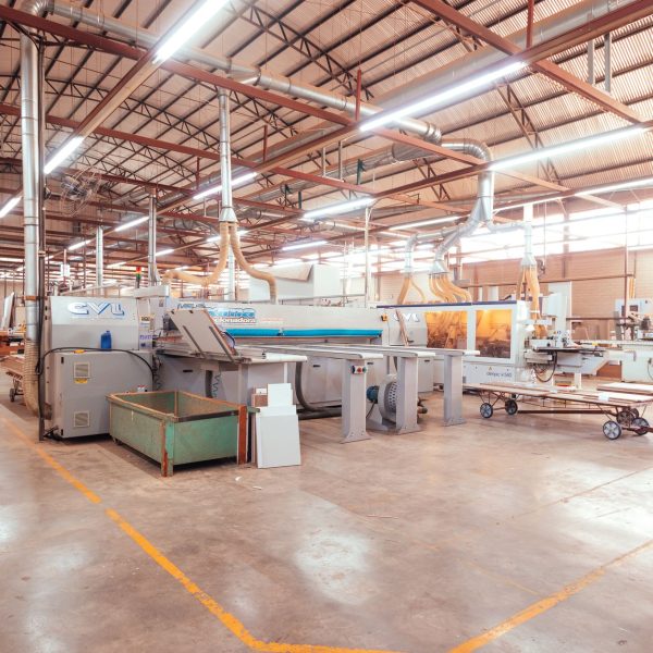 Vista ampla de uma fábrica organizada, com máquinas industriais e áreas de produção.