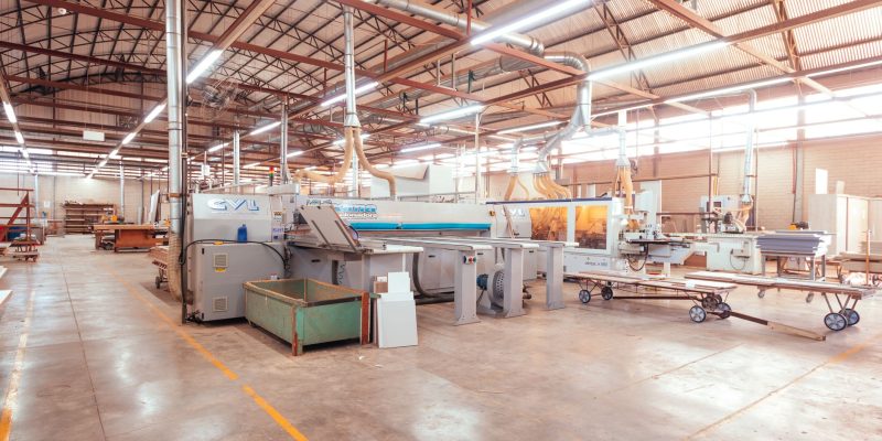Vista ampla de uma fábrica organizada, com máquinas industriais e áreas de produção.